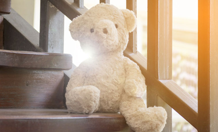 Іграшковий ведмедик сидить на сходах