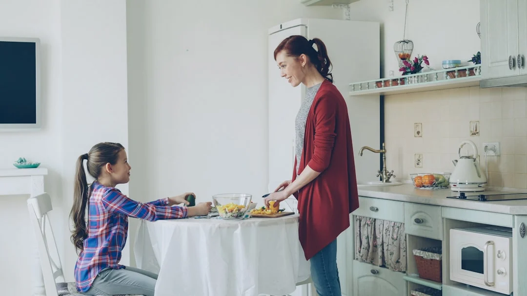 П'ятирічна дівчинка плескає в долоні, рахуючи склади в слові — мама поруч показує на черговий предмет на столі; обидві сміються