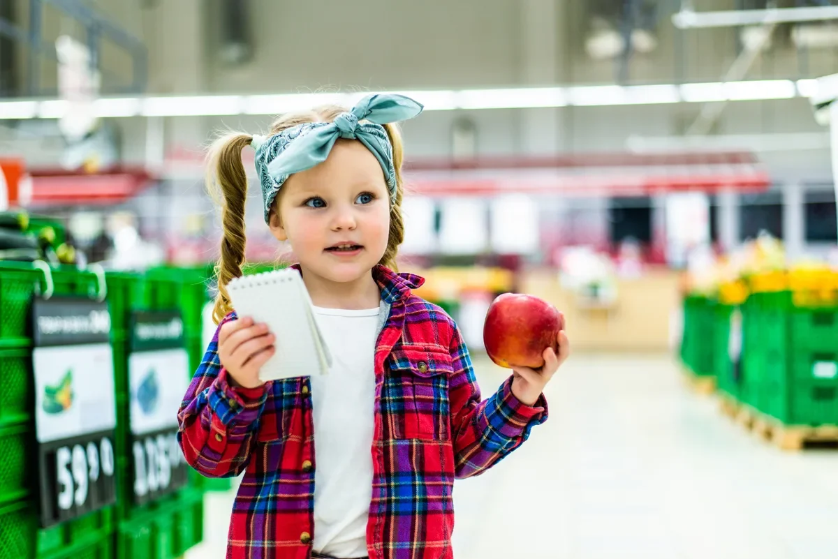Дівчинка знаходить знайоме слово на упаковці у продуктовому магазині, показує мамі